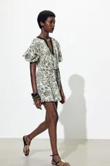 Vestido corto color crema con textura jacquard floral, cuello redondo con escote pico y mangas abullonadas 3/4 con elástico. Incluye cinturón ajustable con lazadas.