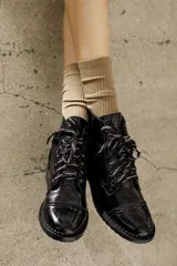 Borcego de cuero vacuno con acabado charol color negro, con cordones y suela de goma.