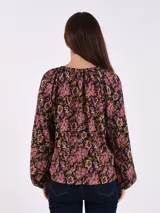 Blusa de manga larga con estampado floral en tonos rosados y oscuros, y detalle de escote en forma de lágrima.