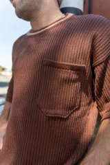 Remera tejida color crudo con cuello redondo con borde verde, mangas cortas y bolsillo en el pecho. Corte holgado.