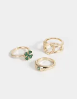 Set de tres anillos dorados con motivos de la buena suerte: uno con tréboles esmaltados, otro con trébol de resina y el tercero con una herradura de metal.