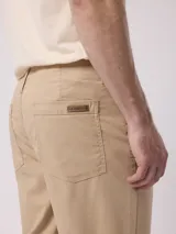 Pantalón de vestir color beige, de corte recto, con bolsillos laterales y traseros. Se ajusta a la cintura con botón y cierre.