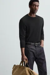Jersey negro de lana con acabado mercerizado, corte relaxed fit, cuello redondo y mangas largas con terminaciones en rib.