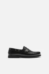 Zapato náutico de cuero negro con cordones de cuero y suela plana.