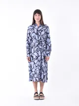 Vestido midi camisero con estampado abstracto en tonos celeste y azul marino. Tiene cuello camisero, mangas largas y lazo en la cintura.