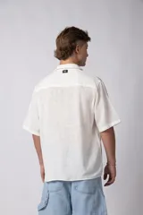 Camisa de lino color blanco, de manga corta, con cuello clásico y cierre frontal con botones.