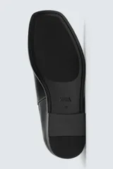 Bota estilo Chelsea de cuero negro, con elásticos laterales y suela plana a tono con ligero tacón.