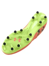 Championes de fútbol Under Armour Magnetico Pro 4 FG, color coral con suela verde lima y logo negro. Diseño con cordones y tecnología que se adapta a la forma del pie.