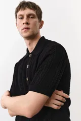 Remera polo negra de manga corta en punto trenzado con cuello clásico, tapeta de botones y bajo recto.