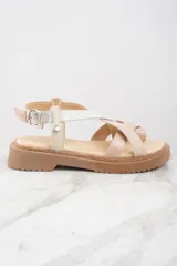 Sandalias con plataforma color beige y suela marrón. Tiras cruzadas en cuero color beige con textura y cuero plateado brillante.