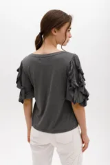 Remera color beige con mangas cortas y volados con borde naranja.