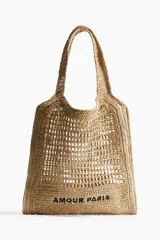 Bolso tipo tote de paja trenzada color beige con asas dobles y la inscripción "Amour Paris" en negro.