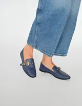 Mocasín azul con detalle de hebilla dorada.