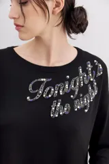 Sweater negro de poliéster, acrílico, poliamida y lana, con calce holgado, mangas largas y terminaciones en punto rib. Presenta bordado de lentejuelas y piedras con la frase "Tonight the night".