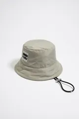 Gorro tipo bucket color gris topo de tejido técnico con cordón ajustable y etiqueta de silicona con el logo de Bimba y Lola.