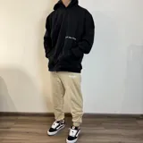 Canguro negro oversize con capucha y bolsillo tipo canguro. Presenta una estampa pequeña con la frase "feel the vibes" en el pecho y un logo en la parte inferior.