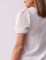 Remera blanca de cuello redondo y mangas cortas abullonadas de microtul bordado con puño elastizado.