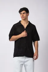 Camisa negra tejida de manga corta, con calado aireado, cuello tipo bowling y botones al tono. Diseño de corte relajado.