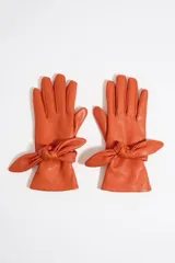 Guantes de piel color naranja con detalle de lazo en la muñeca.