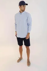 Camisa de hombre color crema, de corte clásico, con cuello abotonado y mangas largas.