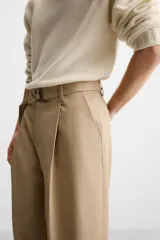 Pantalón negro de corte ancho con cinturón de tela con hebilla metálica y pliegues frontales.