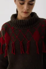 Sweater tejido de punto color crudo con cuello alto y diseño de rombos marrones con flecos.