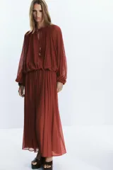 Falda midi color ladrillo, de tiro alto, con plisado fino y estampado de pequeños lunares. Incluye cinturón fino del mismo tejido y forro interior.