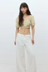 Pantalón jean blanco de tiro bajo, corte holgado en cintura y cadera, con cinco bolsillos y pierna ancha.