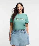 Remera de algodón color verde agua, con cuello redondo, mangas cortas abullonadas y tres corazones de lentejuelas plateadas en el frente.