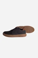 Zapatillas urbanas negras con suela marrón de goma y logo estampado en el lateral.