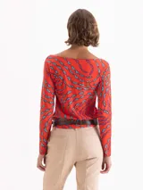 Top de punto color rojo con estampado de labios en azul y fucsia. Presenta escote en V profundo con jareta ajustable para anudar, mangas largas y calce al cuerpo.