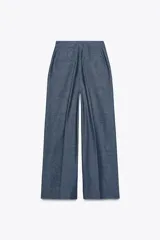 Pantalón ancho azul de tiro alto confeccionado en lino, con bolsillos delanteros con falsos botones y cierre lateral con cremallera oculta.