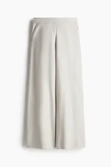 Pantalón ancho color crudo, de tiro alto, con bolsillos laterales y cierre oculto.