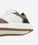 Championes casuales de material sintético color blanco con recortes en marrón, negro y beige. Presentan puntera redonda, cordones y suela contrastante color caramelo.