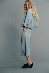 Cazadora de denim celeste con cuello solapa y manga tres cuartos. Cierre frontal con botones metálicos.
