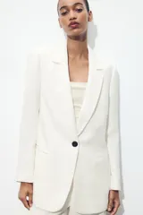 Blazer fucsia de cuello solapa y manga larga con hombreras. Detalle de tejido efecto arrugado. Bolsillos delanteros de vivo. Cierre frontal con un botón.