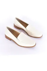 Mocasines de cuero color blanco hueso, con punta almendrada y suela marrón.