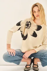 Sweater color crema con estampado de flor en tonos grises y negros en el frente.