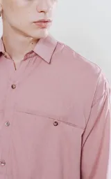 Camisa manga larga color rosa, de calce oversize, con bolsillo con ojal y botón en el delantero.
