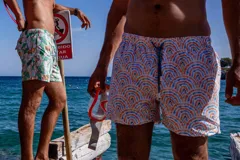Short de baño con estampado de semicírculos concéntricos en tonos naranja, azul y blanco. Cuenta con elástico en la cintura, tres bolsillos y mesh interior hipoalergénico.