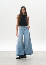 Pantalón de jean celeste de corte mega wide, con cintura alta y ruedo desflecado.