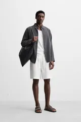 Bermuda regular fit negra confeccionada en tejido de lino. Cintura elástica ajustable con cordón y pliegues frontales. Bolsillos frontales y detalle de bolsillos traseros de plastrón.