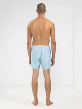 Short de baño celeste con rayas verticales blancas y estampado de flores blancas.