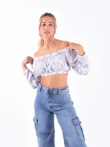 Top corto con hombros descubiertos, mangas largas y estampado floral en tonos celeste y blanco.