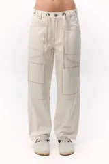 Pantalón jean color crema, de tiro medio, corte recto y pierna ancha. Presenta ajuste con cordones en la cintura y parches a tono con costuras en contraste.