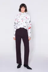 Pantalón de pana color borgoña, de corte recto, largo tobillero y tiro alto con cinco bolsillos. Cierre con cremallera y trabilla para el cinturón.