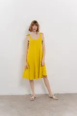 Vestido corto amarillo de lino, con escote en V y tirantes finos con detalle de moño en los hombros.