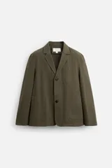 Blazer color verde oliva de algodón con efecto lavado, corte relaxed fit, cuello con solapas de muesca, manga larga y bolsillos frontales de plastrón. Cierre frontal con dos botones.