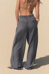Pantalón gris de tejido fluido, tiro alto con cintura tipo paper bag, bolsillos laterales y cinturón lazada en el mismo tejido.