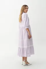 Vestido camisero midi color beige a rayas verticales, con cuello mao, mangas 3/4 abullonadas y festones de algodón en el cuerpo. Cierre frontal con botones.